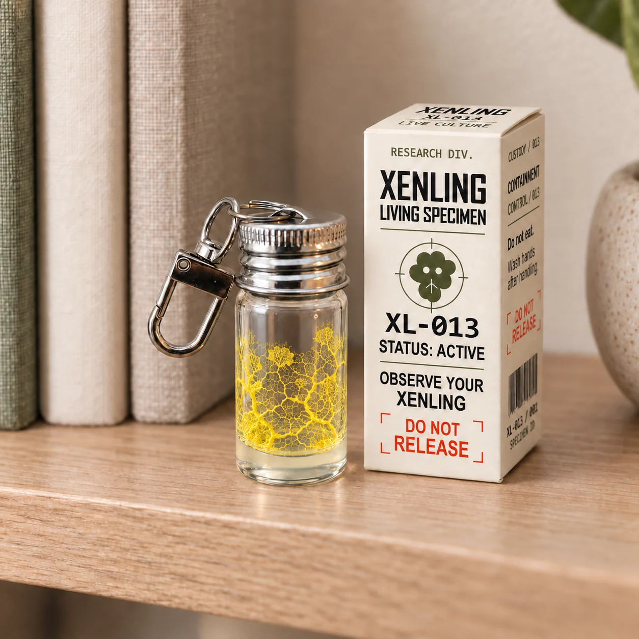 A Xenling glass specimen vial with golden branching slime beside its cream XL-013 box